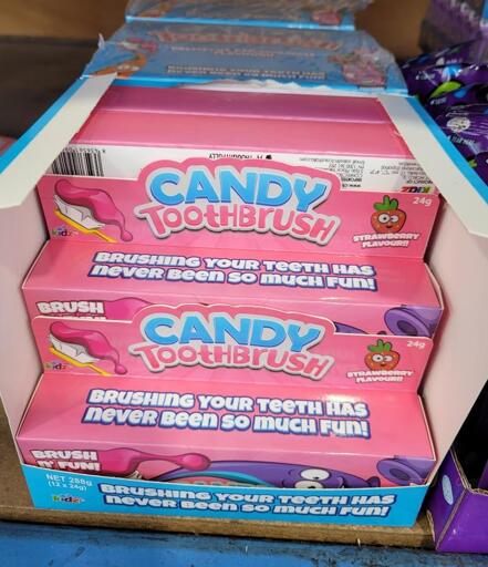 A photo of a bright pink candy box labelled "Candy Toothbrush" with additional text "Brushing your teeth has never been so much fun!"